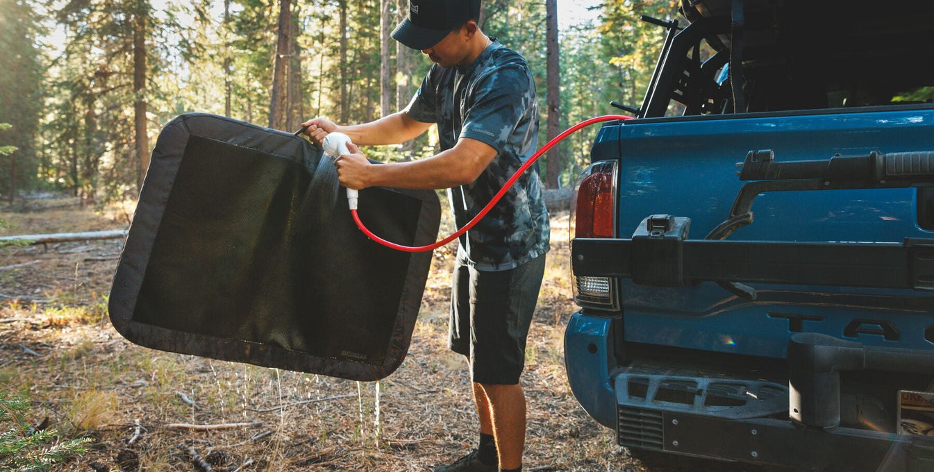 A man washes off his Dirtbag™ Bed with a hose.