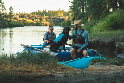 Eddy the lab sits with her humans in their raft.
